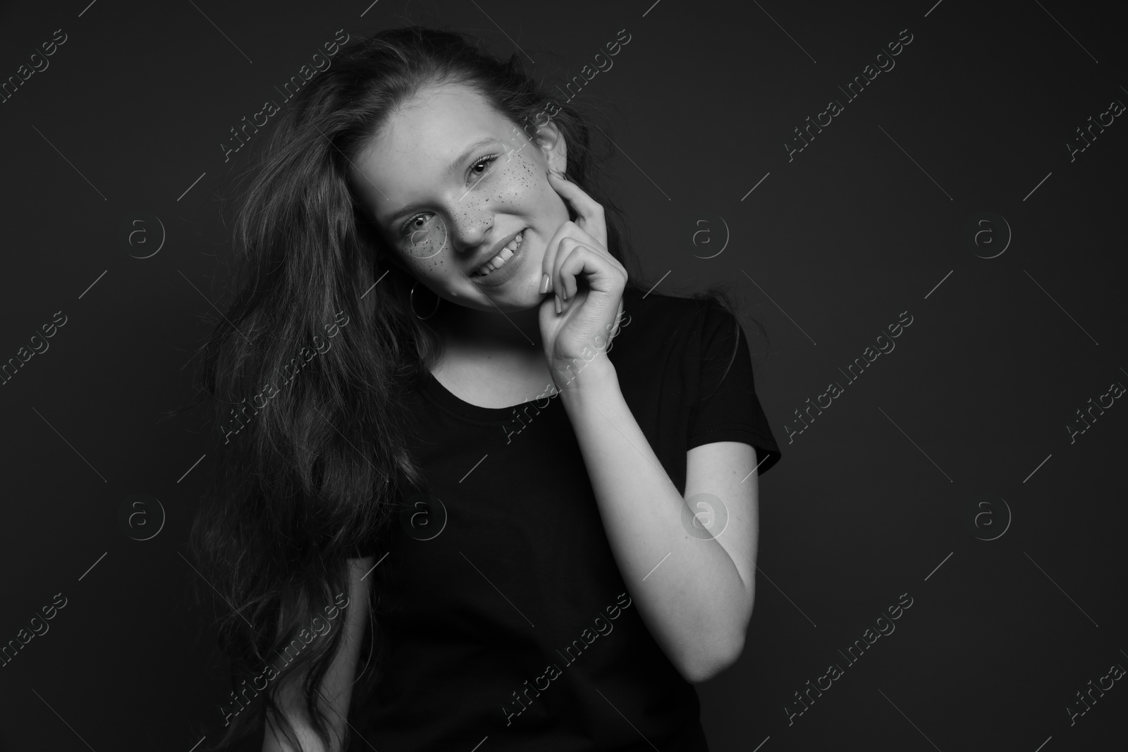 Photo of Beautiful teenage girl with freckles on dark background. Black and white effect