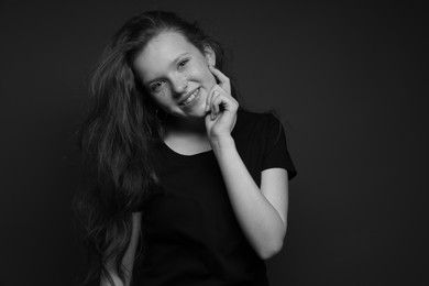 Photo of Beautiful teenage girl with freckles on dark background. Black and white effect