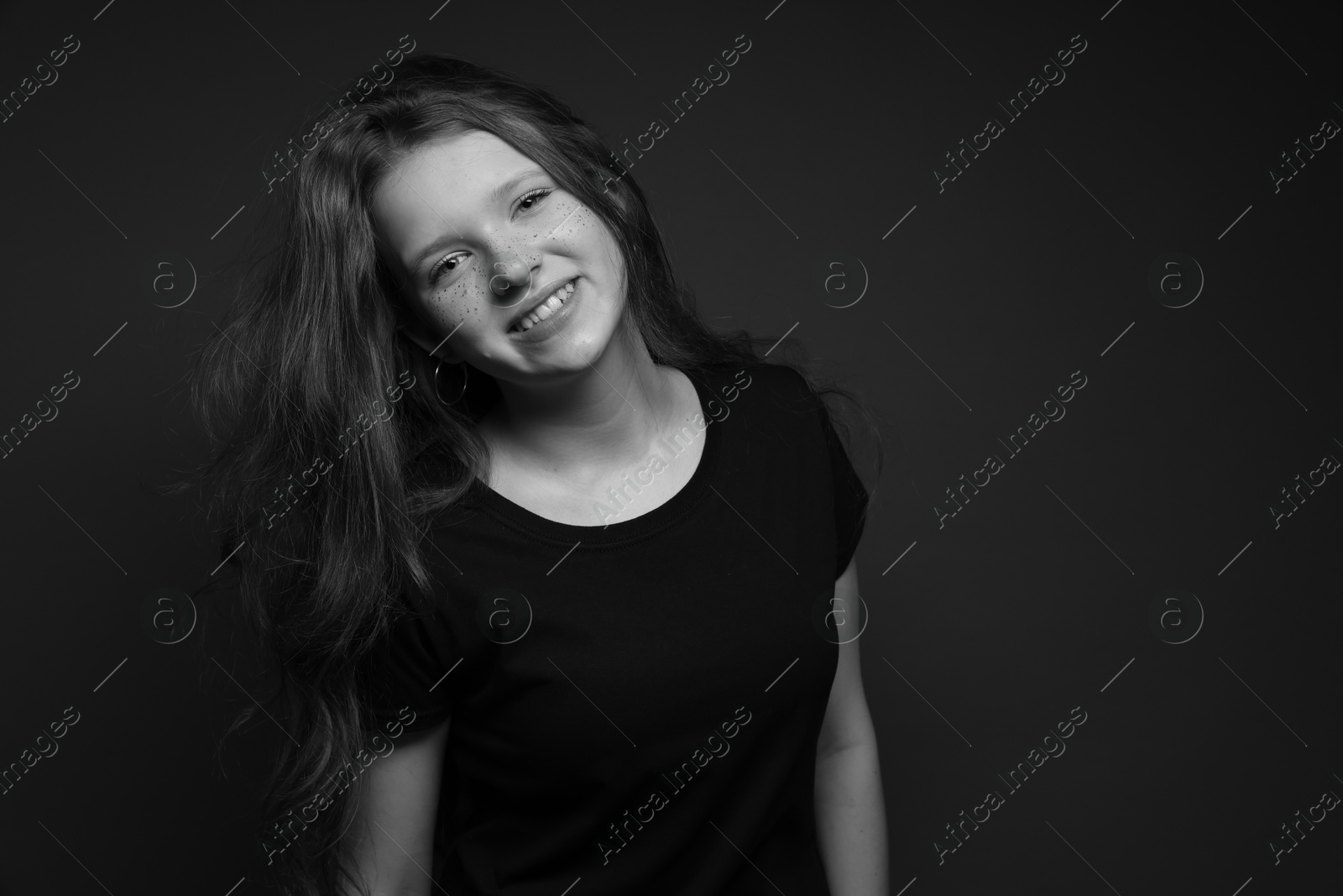 Photo of Beautiful teenage girl with freckles on dark background. Black and white effect