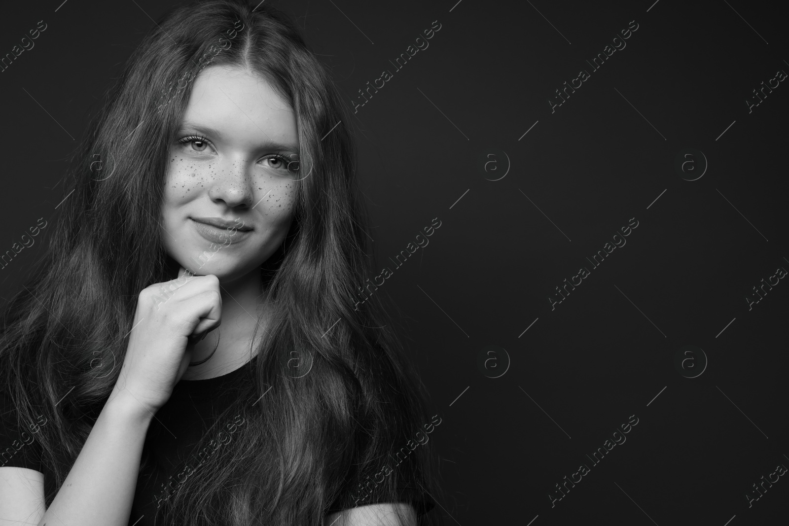 Photo of Beautiful teenage girl with freckles on dark background, space for text. Black and white effect