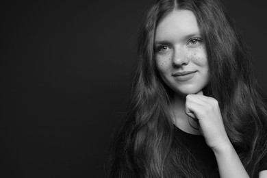 Photo of Beautiful teenage girl with freckles on dark background, space for text. Black and white effect