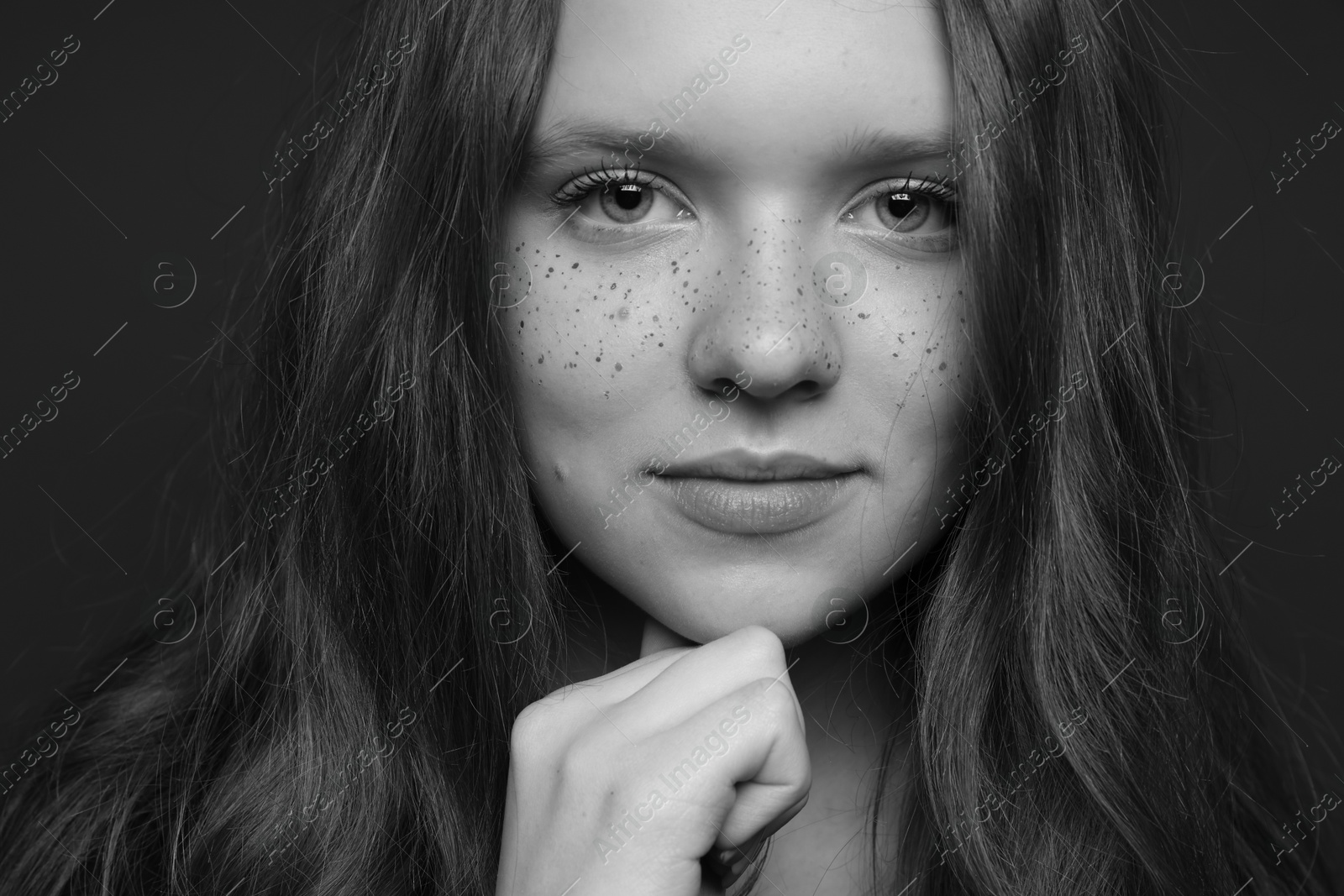 Photo of Beautiful teenage girl with freckles on dark background, closeup. Black and white effect