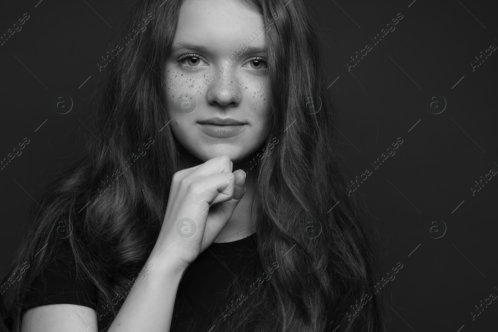 Photo of Beautiful teenage girl with freckles on dark background. Black and white effect