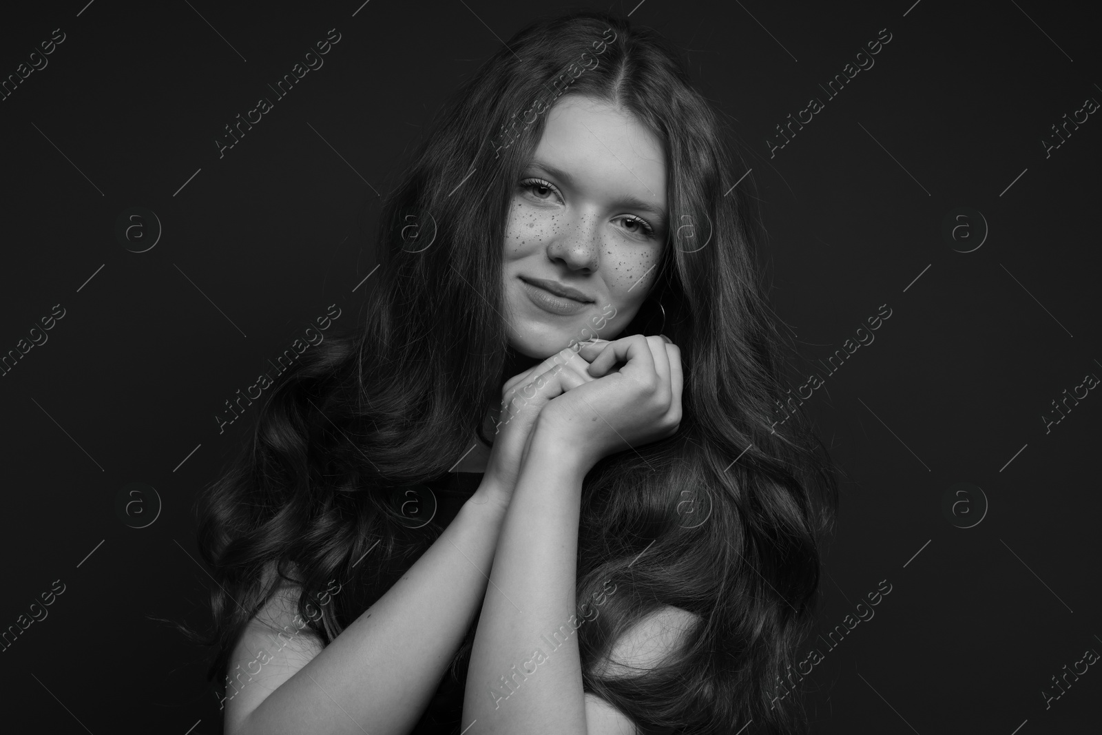 Photo of Beautiful teenage girl with freckles on dark background. Black and white effect