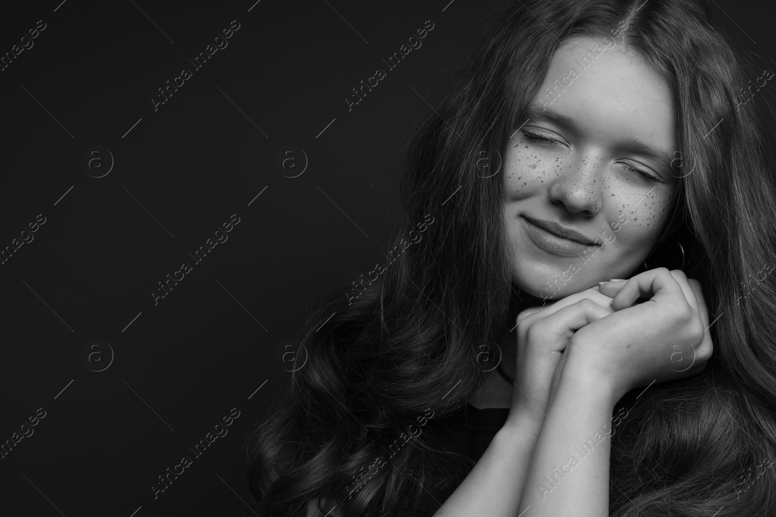 Photo of Beautiful teenage girl with freckles on dark background, space for text. Black and white effect