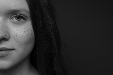 Photo of Beautiful teenage girl with freckles on dark background, closeup and space for text. Black and white effect