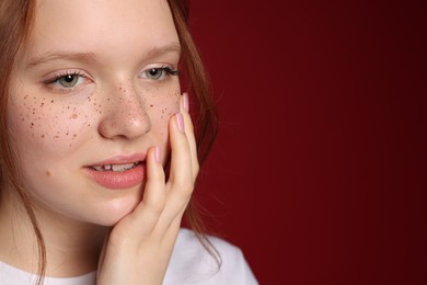 Photo of Beautiful teenage girl with freckles on red background, closeup. Space for text