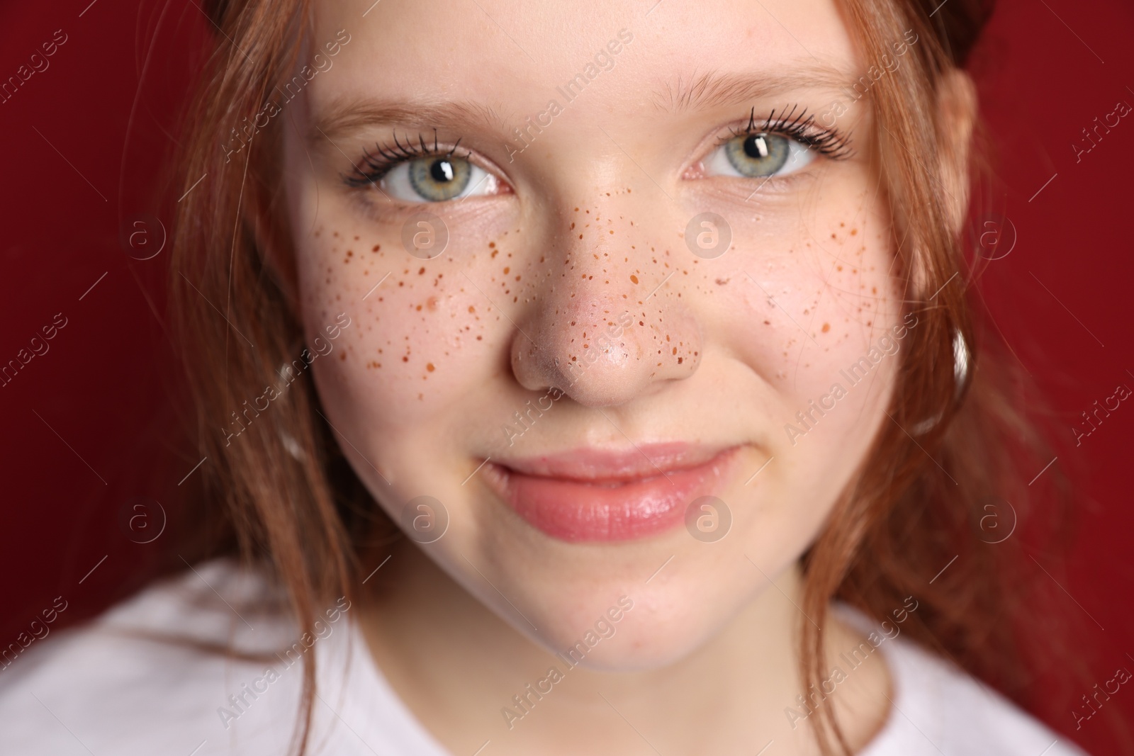 Photo of Beautiful teenage girl with freckles on red background, closeup