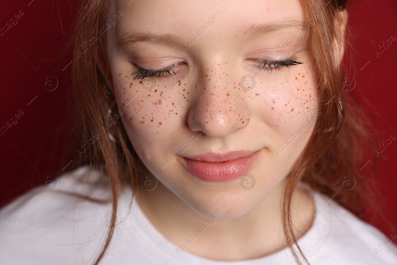 Photo of Beautiful teenage girl with freckles on red background, closeup