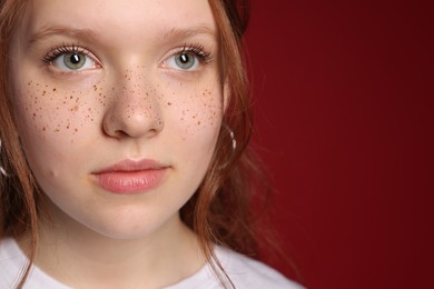 Photo of Beautiful teenage girl with freckles on red background, closeup. Space for text