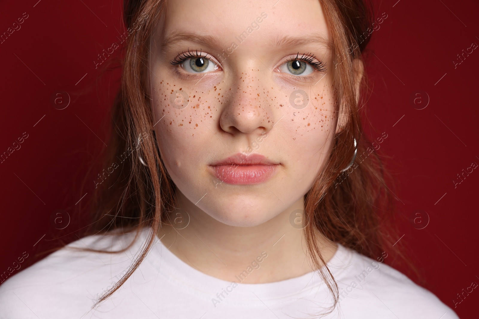 Photo of Beautiful teenage girl with freckles on red background, closeup