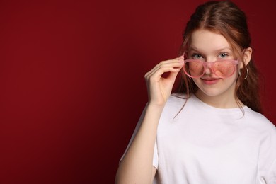 Photo of Beautiful freckled teenage girl with sunglasses on red background, space for text