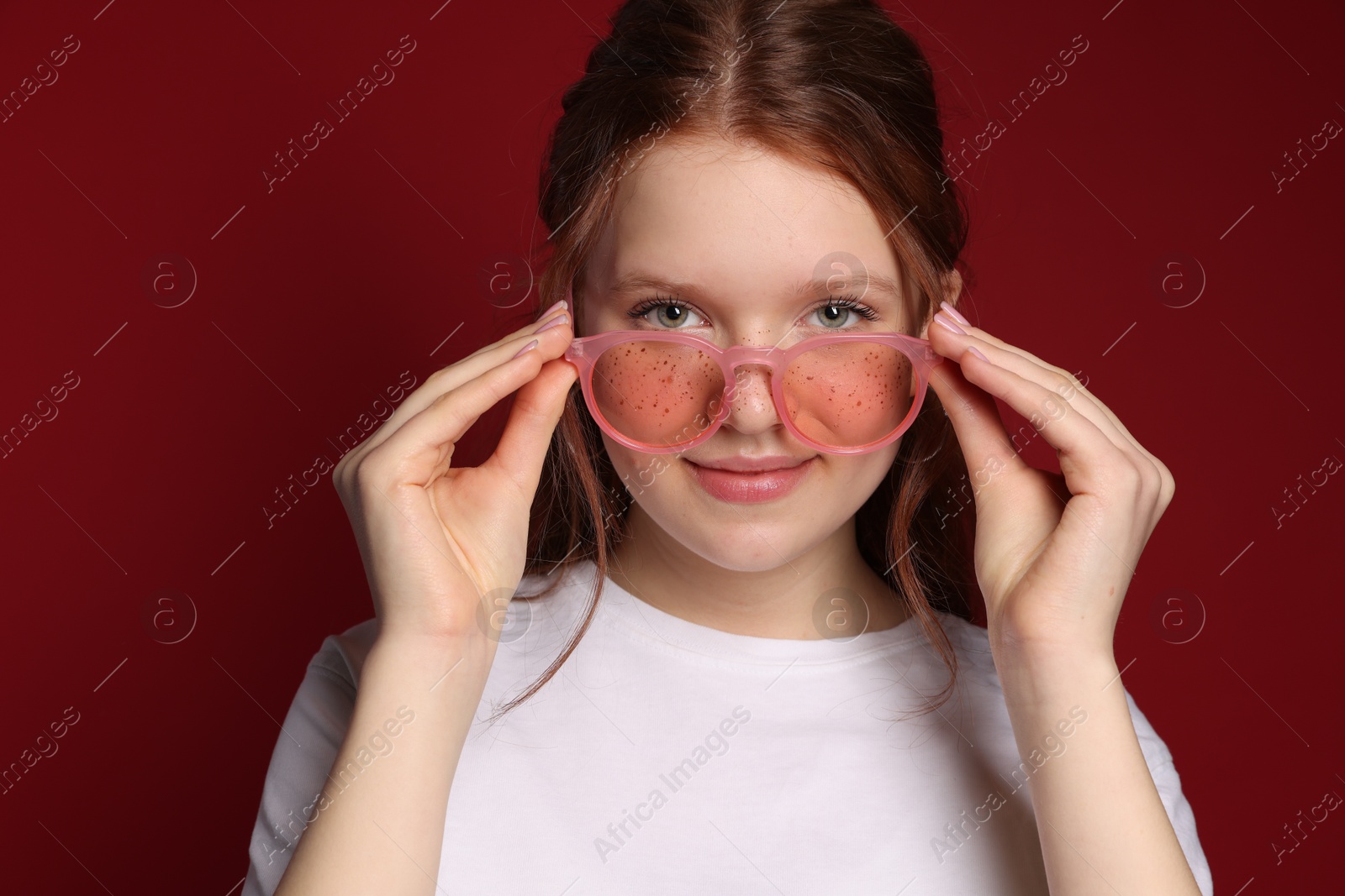 Photo of Beautiful freckled teenage girl with sunglasses on red background