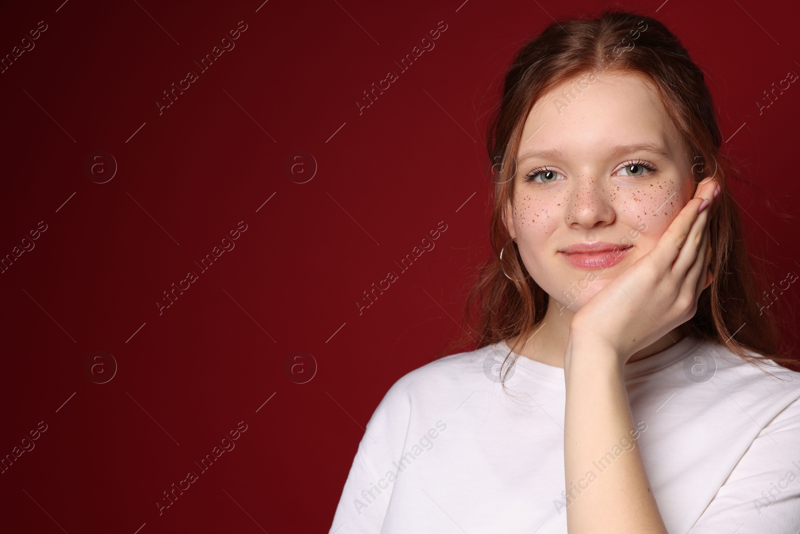 Photo of Beautiful teenage girl with freckles on red background, space for text