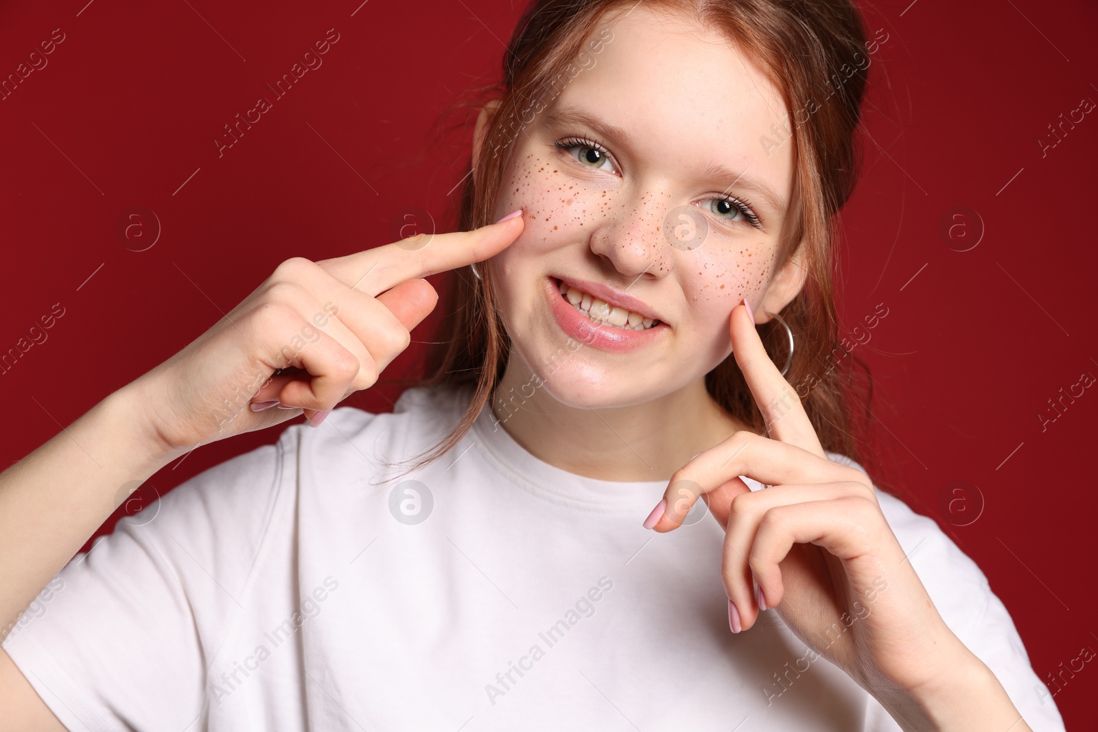 Photo of Beautiful teenage girl with freckles on red background