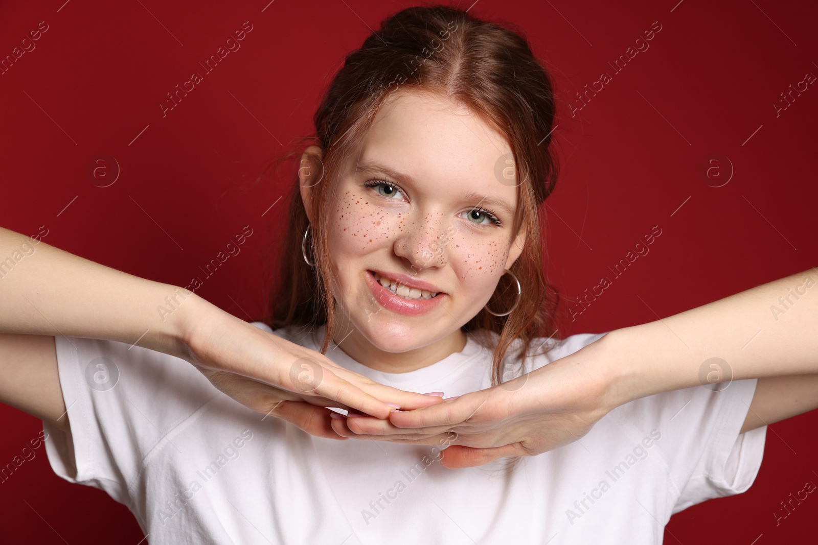 Photo of Beautiful teenage girl with freckles on red background