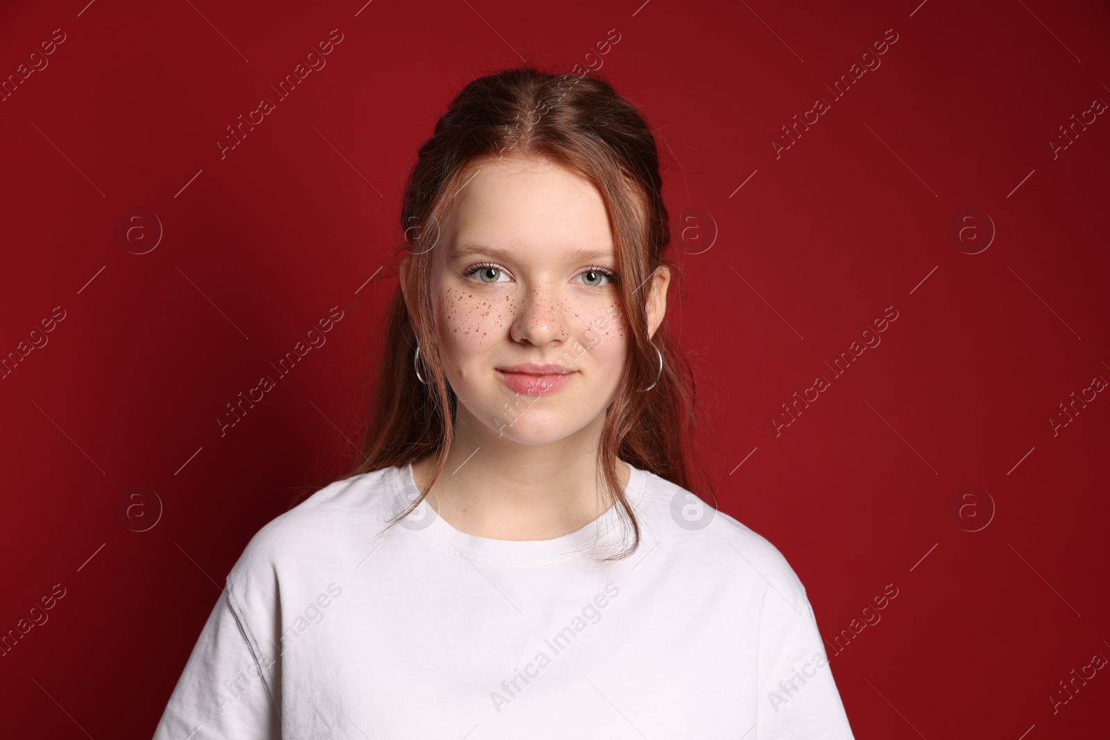 Photo of Beautiful teenage girl with freckles on red background