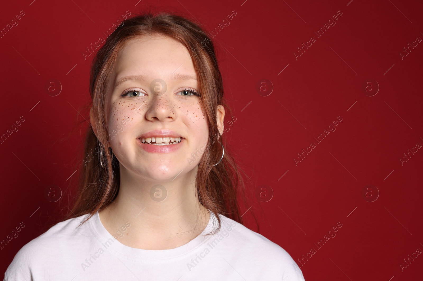 Photo of Beautiful teenage girl with freckles on red background, space for text