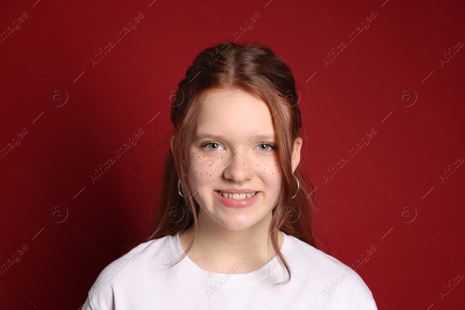 Photo of Beautiful teenage girl with freckles on red background