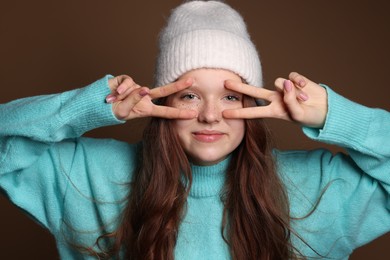 Photo of Cute teenage girl with freckles in hat on brown background