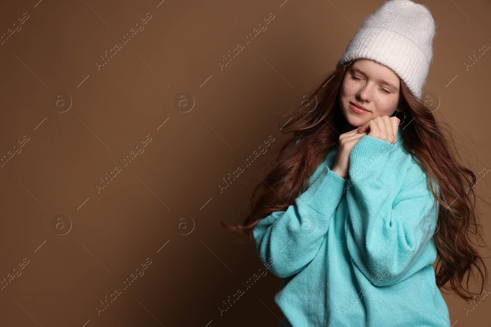 Photo of Beautiful teenage girl with freckles in hat on brown background, space for text