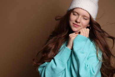 Photo of Beautiful teenage girl with freckles in hat on brown background, space for text