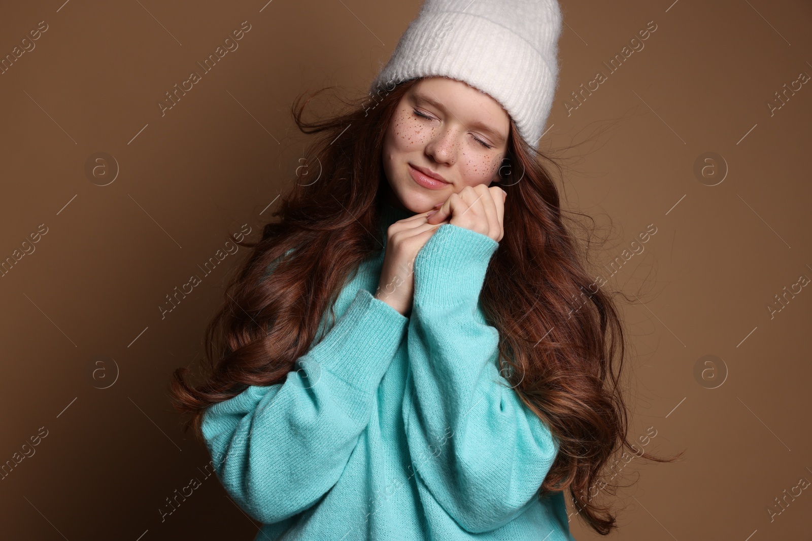 Photo of Beautiful teenage girl with freckles in hat on brown background