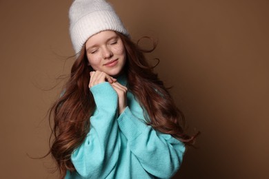 Photo of Beautiful teenage girl with freckles in hat on brown background