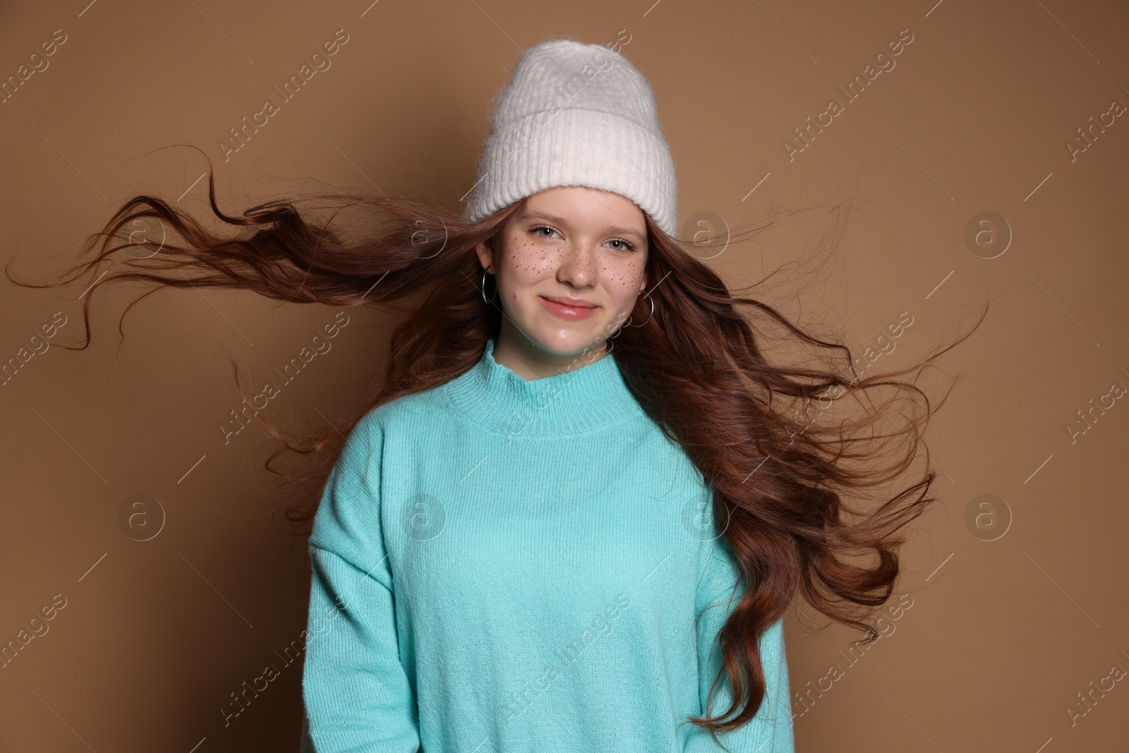 Photo of Beautiful teenage girl with freckles in hat on brown background