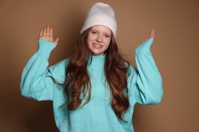 Photo of Beautiful teenage girl with freckles in hat on brown background