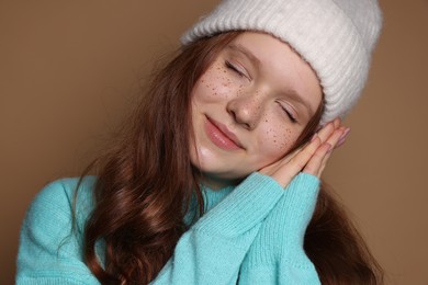 Photo of Beautiful teenage girl with freckles in hat on brown background, closeup