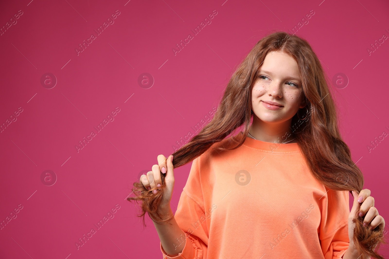 Photo of Beautiful teenage girl with freckles on pink background, space for text