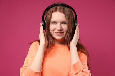 Photo of Beautiful freckled teenage girl with headphones on pink background