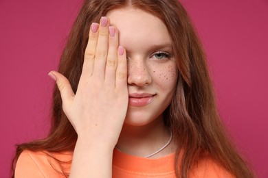 Photo of Beautiful teenage girl with freckles on pink background, closeup