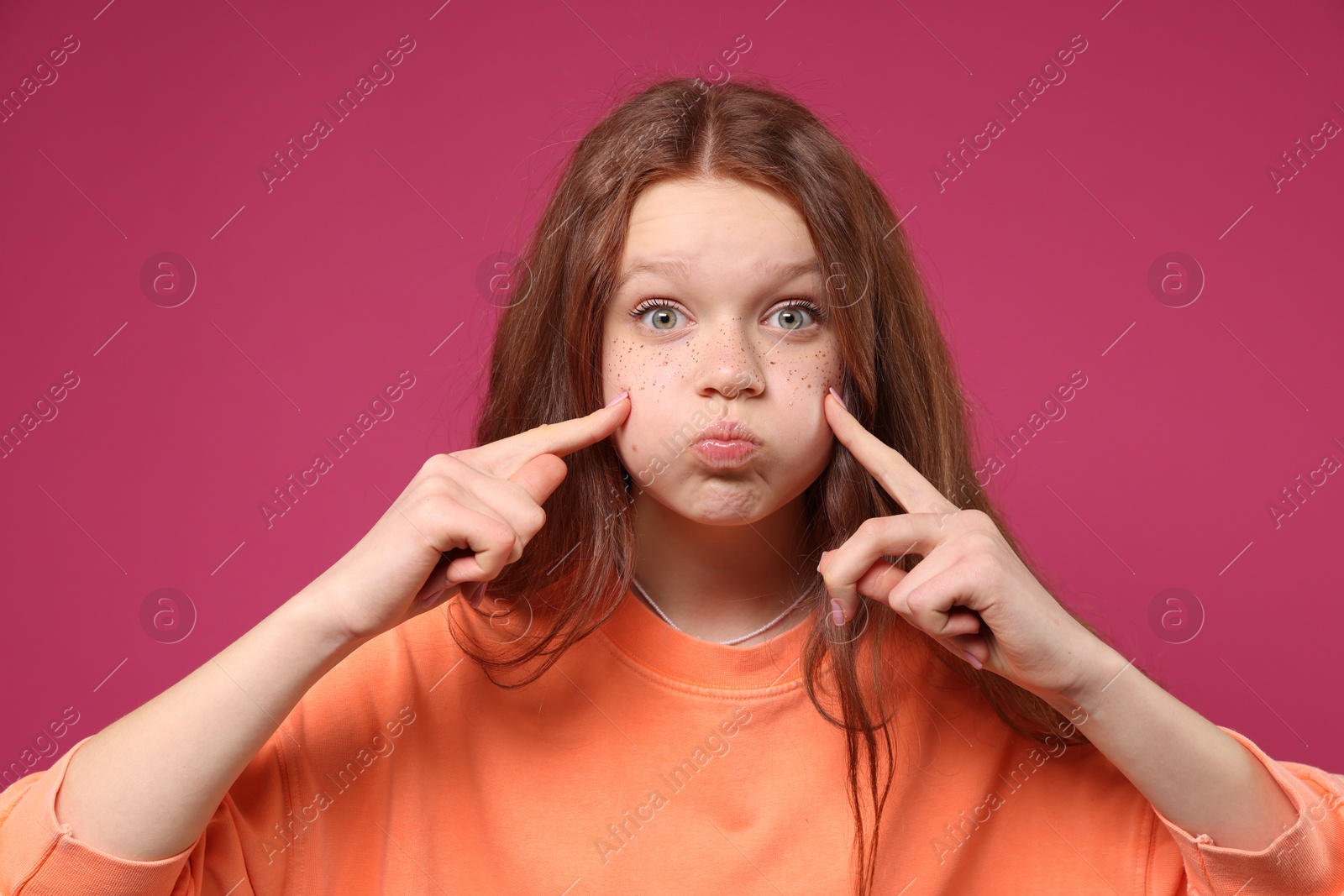 Photo of Cute teenage girl with freckles on pink background