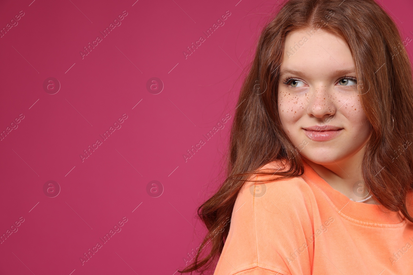 Photo of Beautiful teenage girl with freckles on pink background, space for text