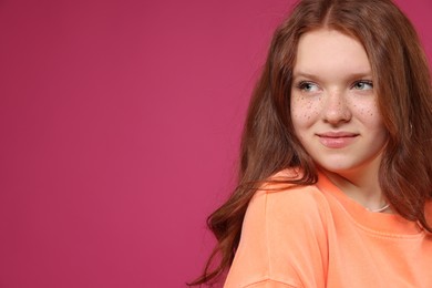 Photo of Beautiful teenage girl with freckles on pink background, space for text