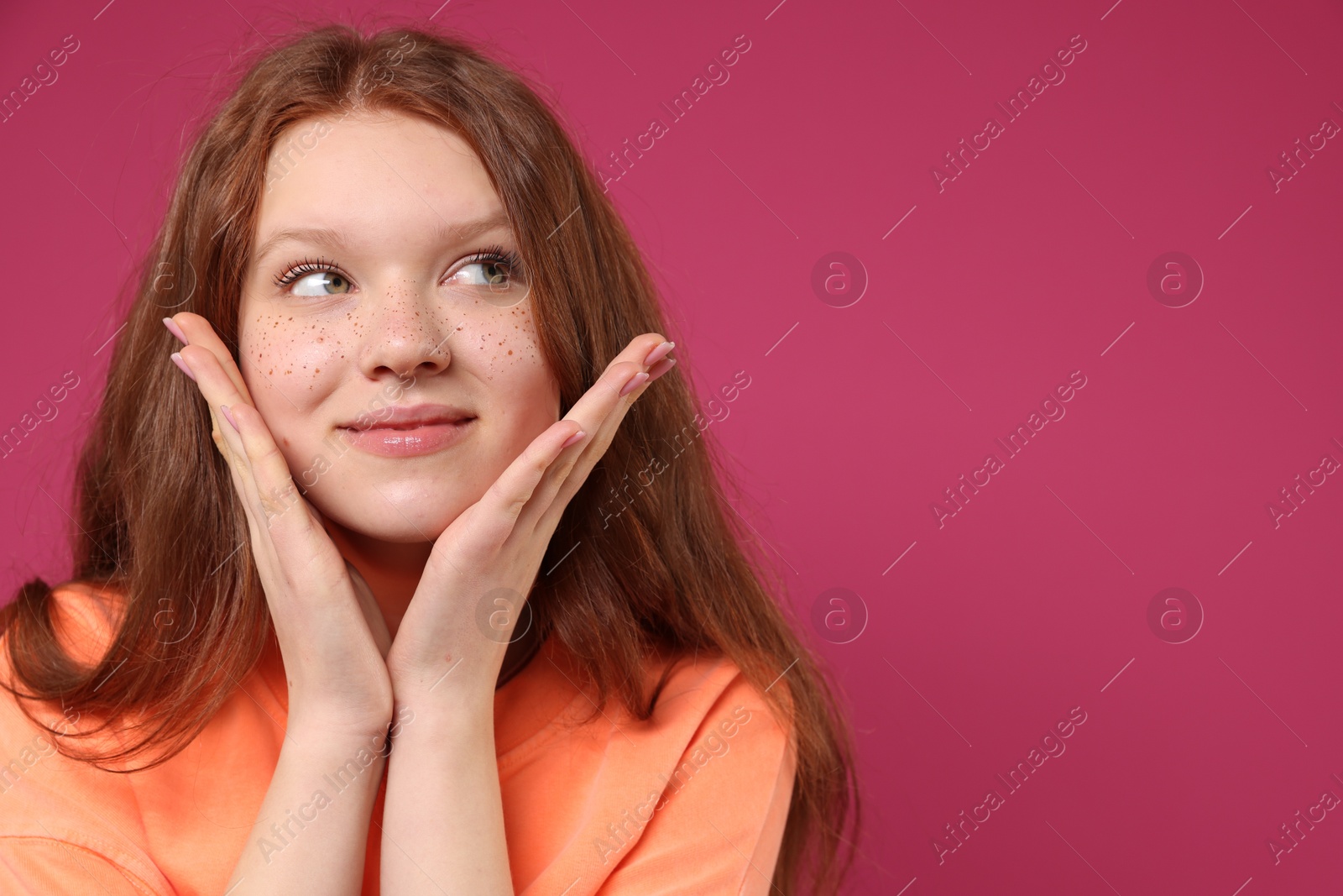 Photo of Beautiful teenage girl with freckles on pink background, space for text