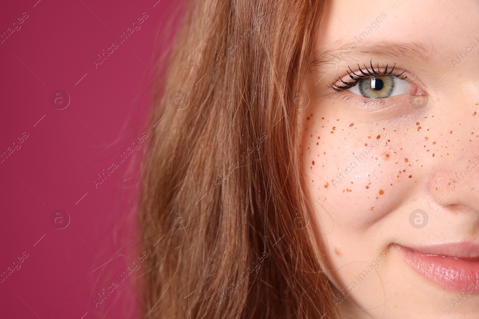 Photo of Beautiful teenage girl with freckles on pink background, closeup