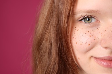 Photo of Beautiful teenage girl with freckles on pink background, closeup