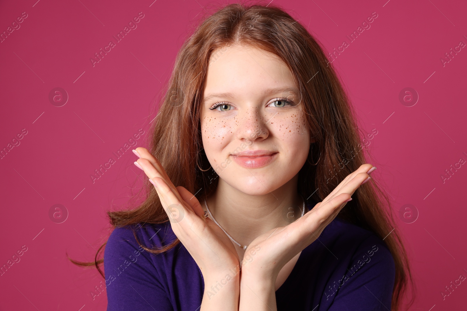 Photo of Beautiful teenage girl with freckles on pink background