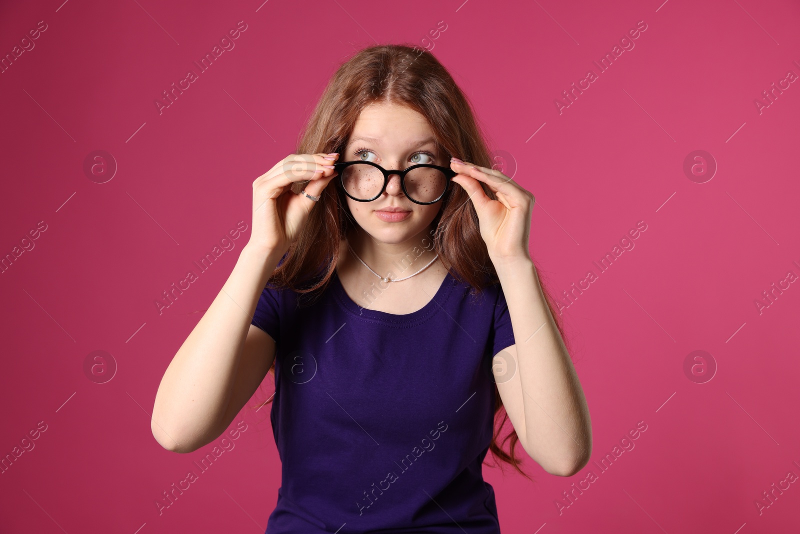 Photo of Beautiful freckled teenage girl with glasses on pink background