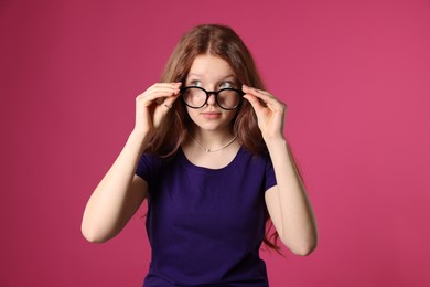 Photo of Beautiful freckled teenage girl with glasses on pink background