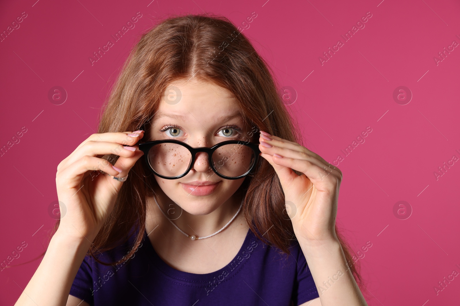 Photo of Beautiful freckled teenage girl with glasses on pink background