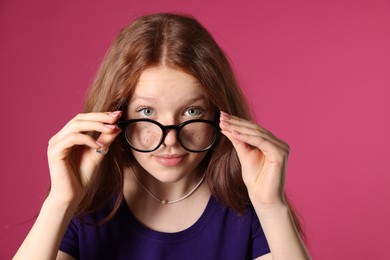 Photo of Beautiful freckled teenage girl with glasses on pink background