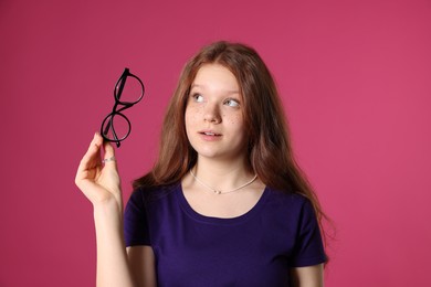 Photo of Beautiful freckled teenage girl with glasses on pink background