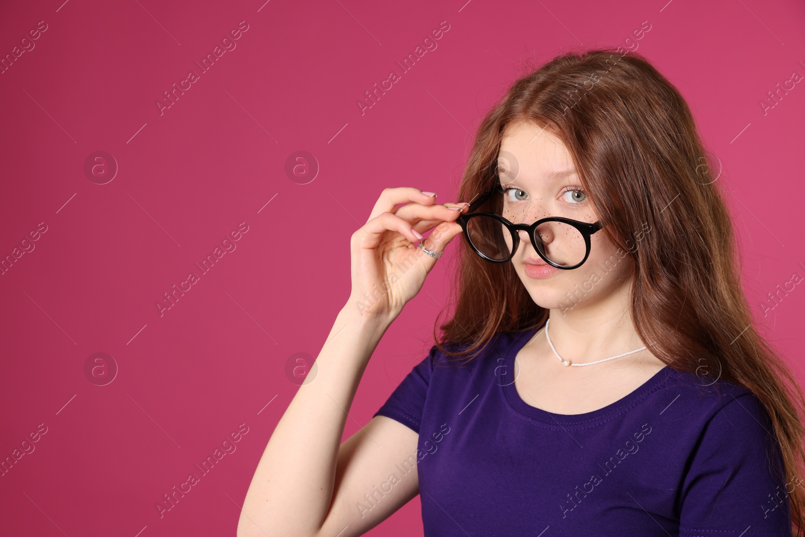 Photo of Beautiful freckled teenage girl with glasses on pink background, space for text