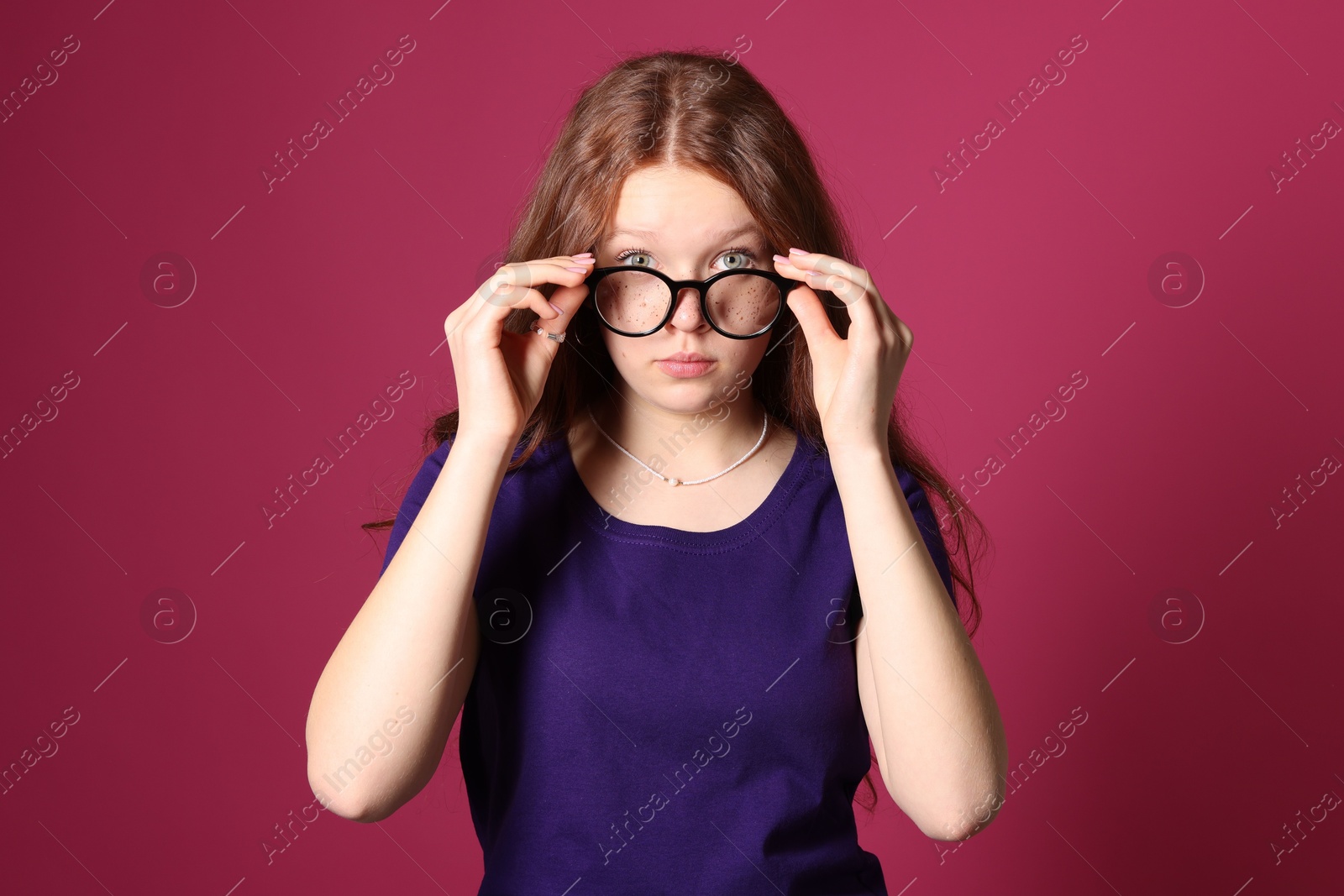 Photo of Beautiful freckled teenage girl with glasses on pink background