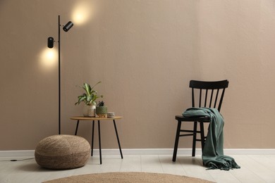 Photo of Stylish room interior with pouf, chair and houseplants