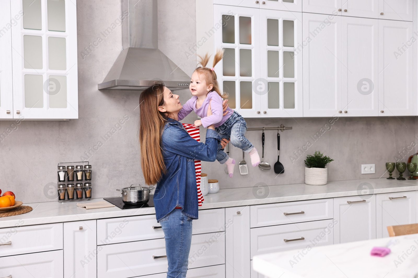 Photo of Housewife playing with her little daughter in kitchen